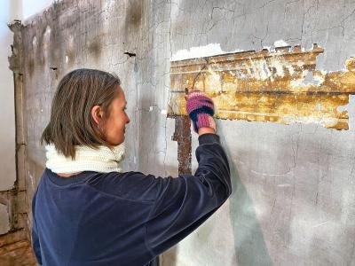 Restauratrice Irina Kudriavchenko legt de eeuwenoude muurschildering van een lambrisering bloot. © Cis Marinus